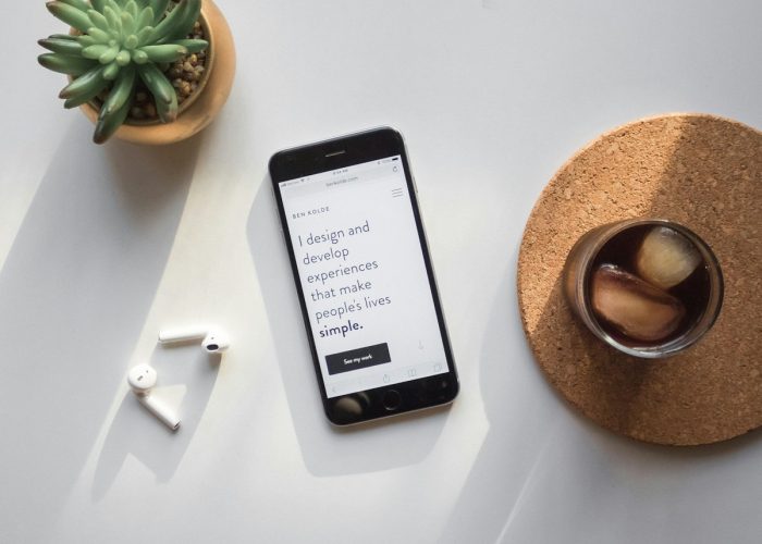 post-2014 iPhone beside Apple AirPods and succulent plant on white surface